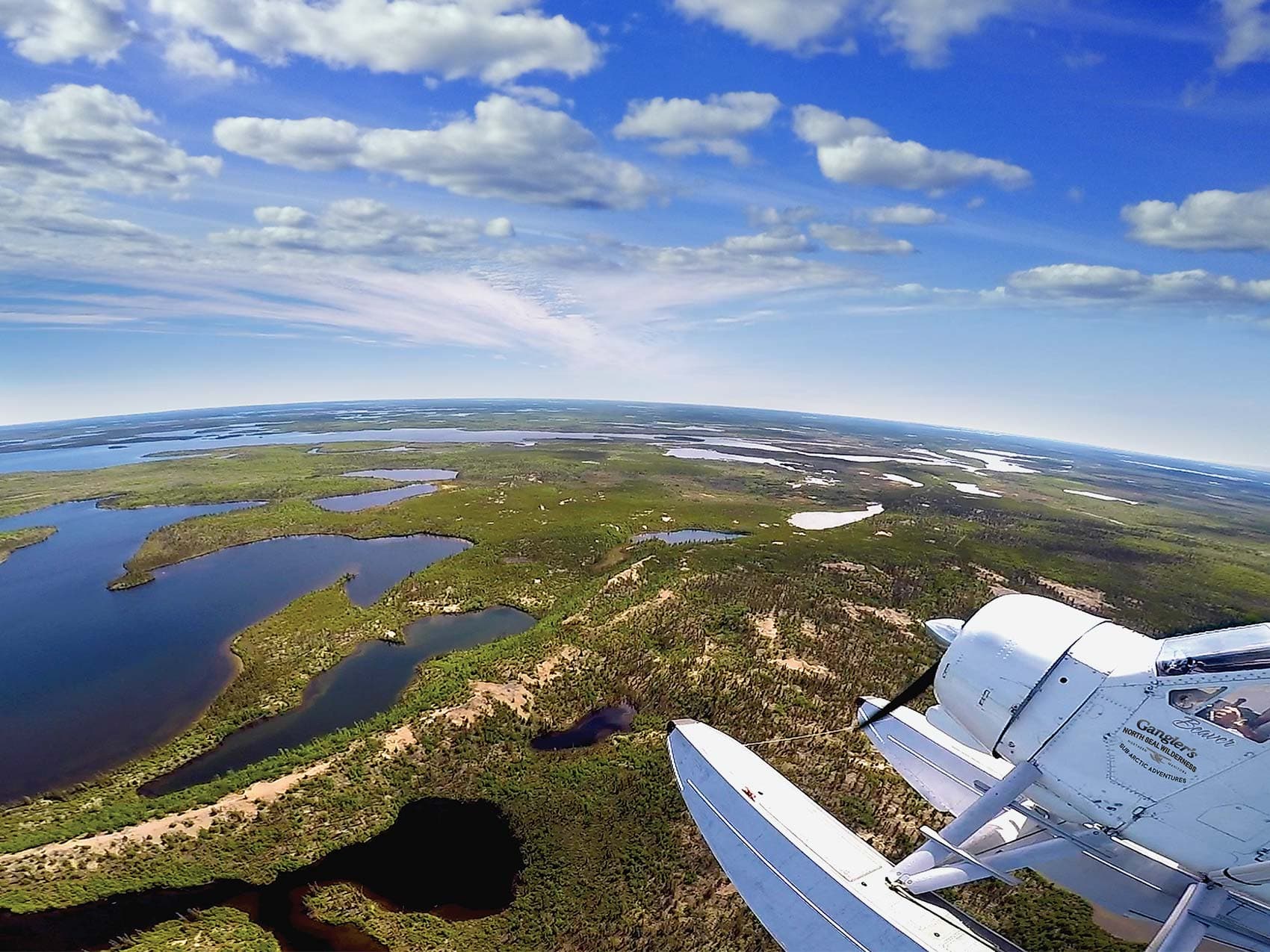 aerial image on the wing of a float plane in flight over the North Seal River lodge