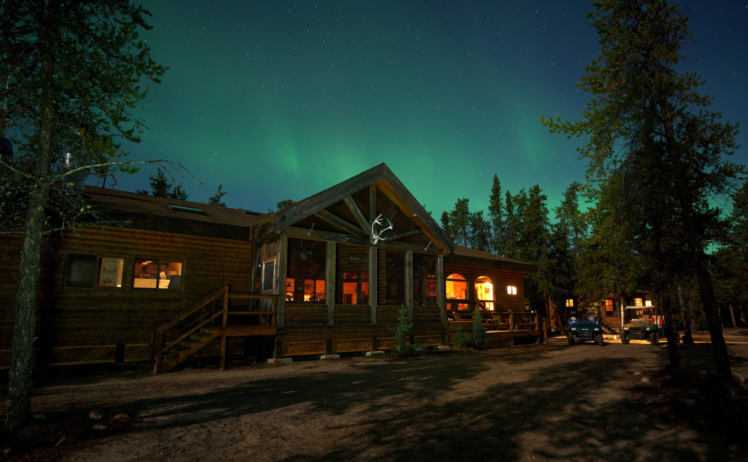 landscape image of the main lodge at night with green northern lights in the sky